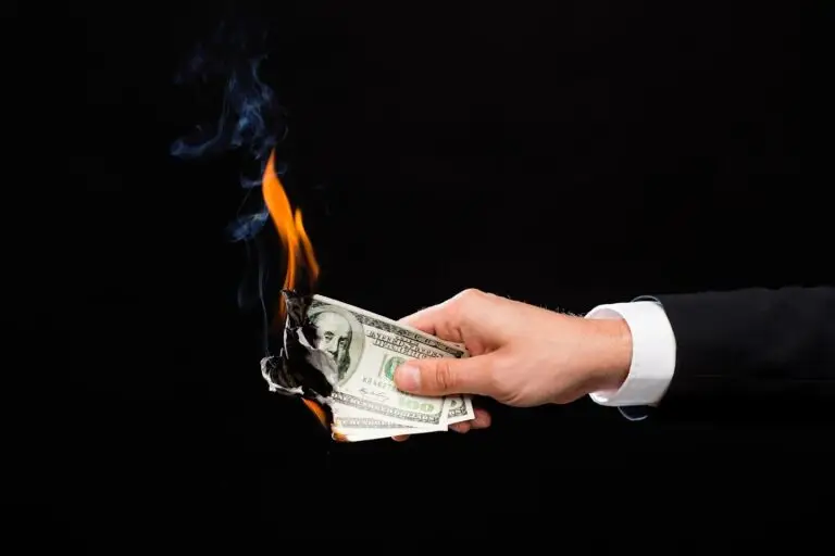 man holding money that is on fire or burning